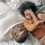 Canva - Ethnic dad and kid resting together on bed