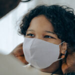 Canva - Father putting on face mask on son